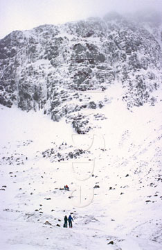 Comp image : ld02120 : In the English Lake District, distant climbers look up at the snow covered face of Great End, near Scafell Pike