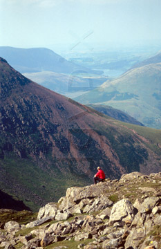 Comp image : ld03906 : A walker in red rests in the summer sun on High Stile (over Buttermere) in the English Lake District. Red Pike in the background.