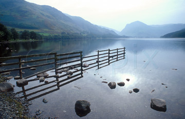 Comp image : ld05320 : Morning autumn sun and reflection of a fence and rocks in the still surface of Buttermere lake, in the English Lake District, with Fleetwith Pike in the distance
