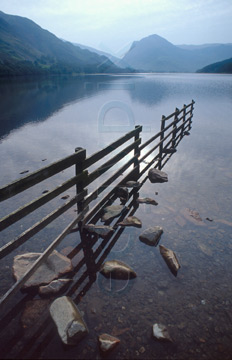 Comp image : ld05323 : Morning autumn sun and reflection of a fence and rocks in the still surface of Buttermere lake, in the English Lake District, with Fleetwith Pike in the distance