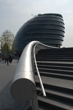 Comp image : lond010059 : Dramatic view, against the light, looking along a curved wall and handrail to London's City Hall on the south bank of the River Thames