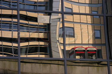 Comp image : lond010074 : Distorted reflection in the glass of a London building, with two red telephone boxes