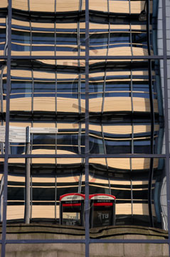 Comp image : lond010081 : Distorted reflection in the glass of a London building, with two red telephone boxes