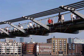 Comp image : lond010090 : People walking in sunshine on the Millennium Bridge over the River Thames in London, England, with buildings on the north bank of the river in the backgound
