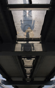 Comp image : lond010106 : Spooky shapes and shadows under the Millennium Bridge over the Thames in London, as a man walks on the bridge in the sunshine