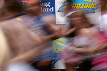 Comp image : mar022126 : The blur of runners in the London Marathon, with parts of roadside advertisements in the background