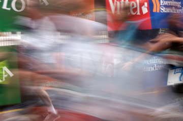 Comp image : mar022130 : The blur of runners in the London Marathon, with parts of roadside advertisements in the background