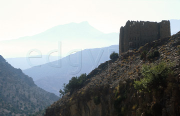 Comp image : mgun0515 : A Berber grain store building high on a hillside in the High Atlas mountains of Morocco, in partial silhouette against distant hills