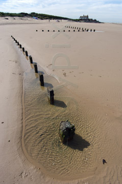 Comp image : shor022789 : A zigzag line of wooden posts in sunshine on a deserted sandy beach at low tide on the flat North Norfolk coast of England, under a clear blue sky