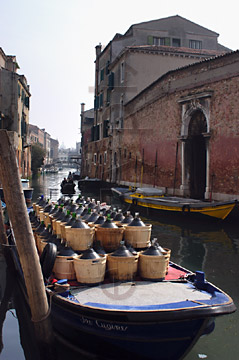Comp image : ven021507 : A barge heavily loaded with large wine bottles is moored on a canal in the Cannaregio area of Venice, Italy, on a bright sunny day