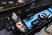 Looking down on a gondola on a canal in Venice, Italy; a straw gondolier's hat with a red ribbon lies on the seat