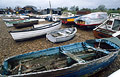 Boats on the shingle on the Suffolk shore, the foreground boat in poor condition with peeling blue paint