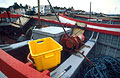 Ropes and tackle in a red and pale blue fishing boat on the shore at Aldeburgh, Suffolk, England, with a bright yellow box