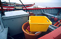 Ropes and tackle in a red and pale blue fishing boat on the shore at Aldeburgh, Suffolk, England, with a bright yellow box