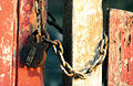 Padlock and chain on old peeling red and white painted gates