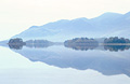 A perfect reflection of distant misty fells in Derwentwater, in the English Lake District