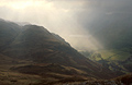 Sun breaking through heavy cloud over Brothers Water and dark Lake District fells near Patterdale