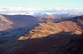 Lingmoor Fell, in the Lake District, catches the winter sun in this view from Pike O'Blisco towards Langdale, with the Hellvellyn range under snow in the distance