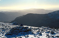 Looking south-west into the winter sun from snow-covered Scafell Pike in the English Lake District