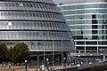 People enjoy the sun at City Hall in the 'More London' development between London Bridge and Tower Bridge on the south bank of the River Thames, London, England