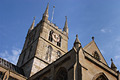 Dramatic view looking up to the tower of Southwark Cathedral in London, England, in strong sun against a blue sky