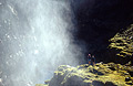 Spray from a waterfall over the Markarfljót Gorge [Markarfljot Gorge], Iceland. Two figures stand just out of reach.