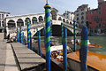 The Rialto Bridge [Ponte di Rialto] (built 1591) over the Grand Canal [Canal Grande] in Venice, Italy, with boats and striped blue/green water markers in the foreground