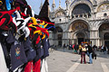 Colourful carnival hats on a stall in St Marks Square [Piazza San Marco] in Venice, Italy, with tourists outside the Basilica San Marco in the background
