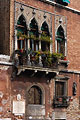 Part of an old red brick building with stone Moorish style windows and a balcony in Venice, Italy