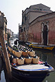 A barge heavily loaded with large wine bottles is moored on a canal in the Cannaregio area of Venice, Italy, on a bright sunny day