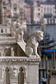 Carved lions on balconies of the Ca' d'Oro (built 1421 - 1440) overlooking the Grand Canal [Canal Grande] in Venice, Italy, with gondolas and old buildings out of focus in the background