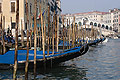 Gondolas moored in sunshine on the Grand Canal [Canal Grande] in Venice, Italy, with the Rialto Bridge in the background