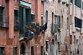 Old red ochre buildings with jumbled windows beside a canal in Venice, Italy, with brick showing through the plasterwork, damaged by damp and high water